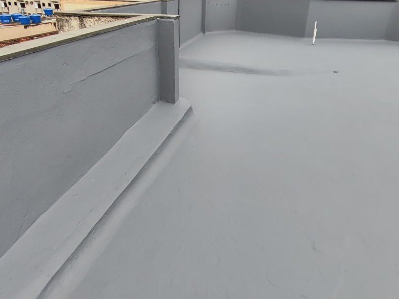Terraço impermeabilizado com revestimento cinza contínuo aplicado sobre a superfície e rodapés.