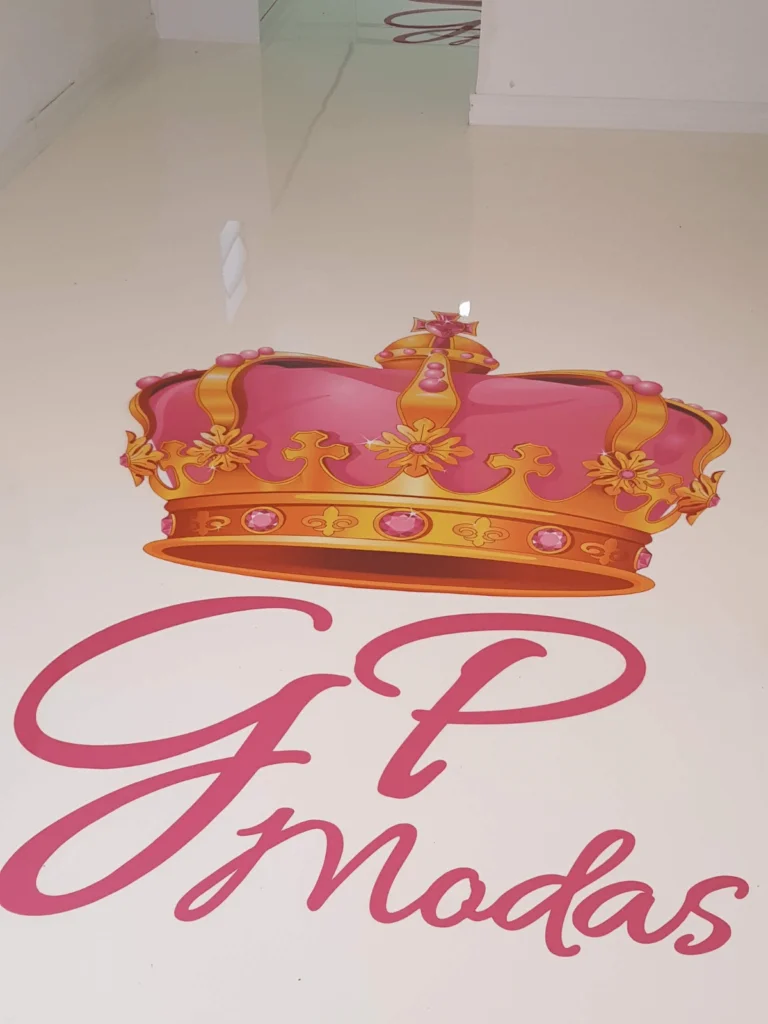 Piso epóxi branco brilhante com arte personalizada mostrando uma coroa rosa e dourada e o texto “GP Modas”.