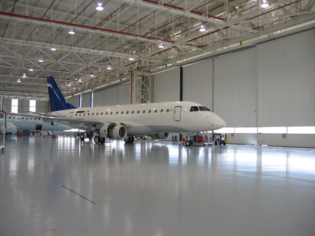 Piso industrial epóxi em hangar aeronáutico, garantindo segurança, excelente refletância luminosa e alta durabilidade em operações de manutenção.
